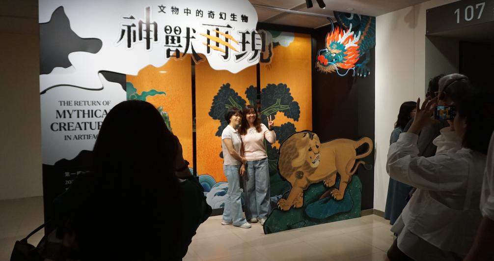 5月21日，在台北故宫博物院的“神兽再现—文物中的奇幻生物”特展入口处，参观者和主题展板合影留念。新华社记者褚萌萌摄